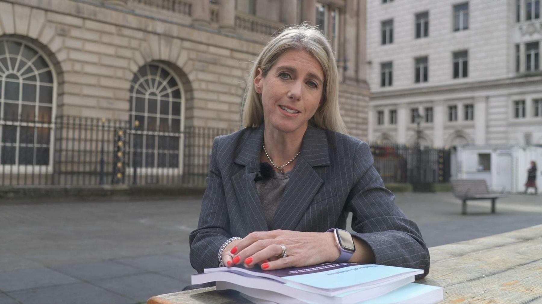 Blond woman sitting at table with arms over books