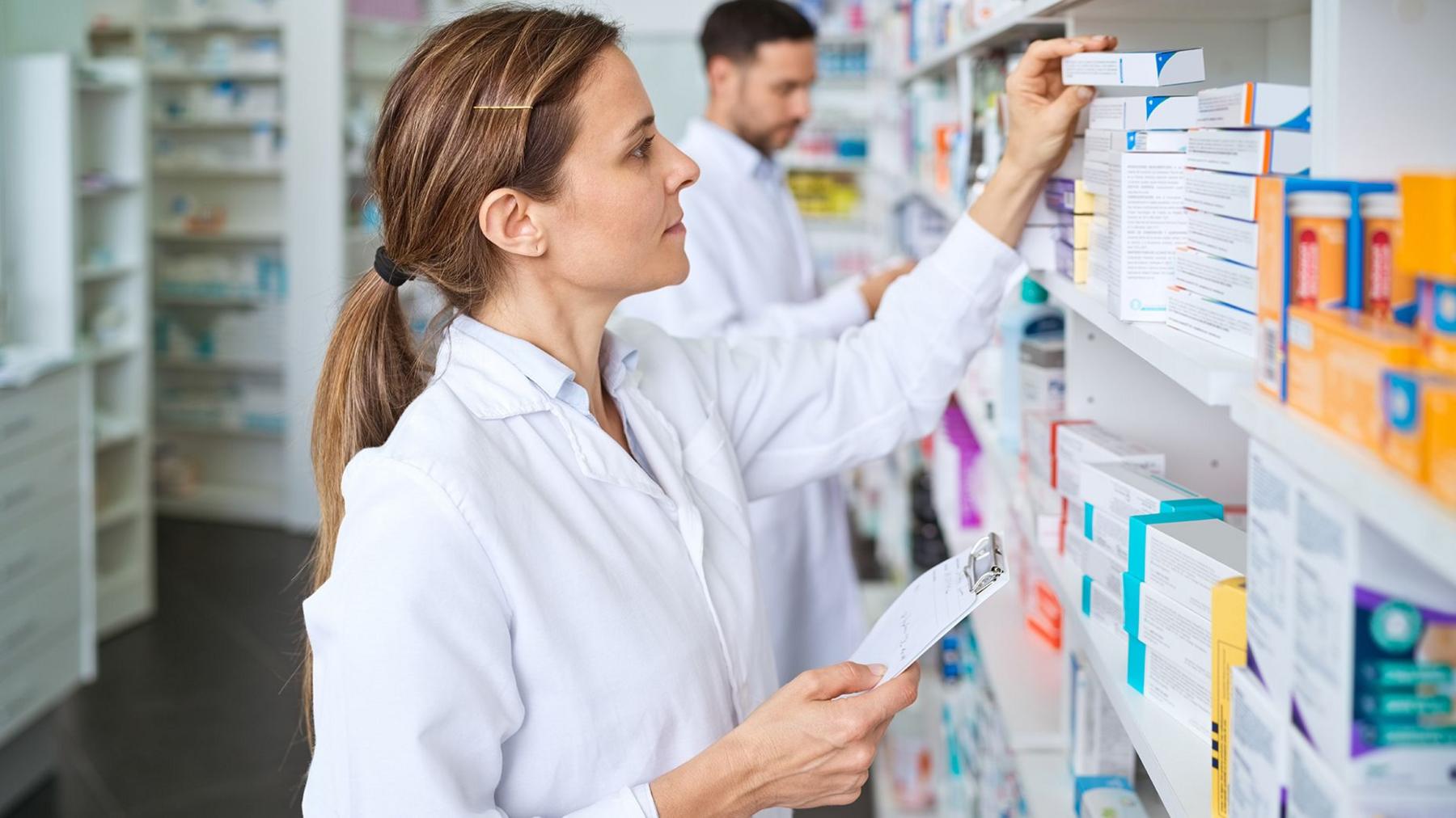 A pharmacist looks at rows of medicines and pilss in boxes