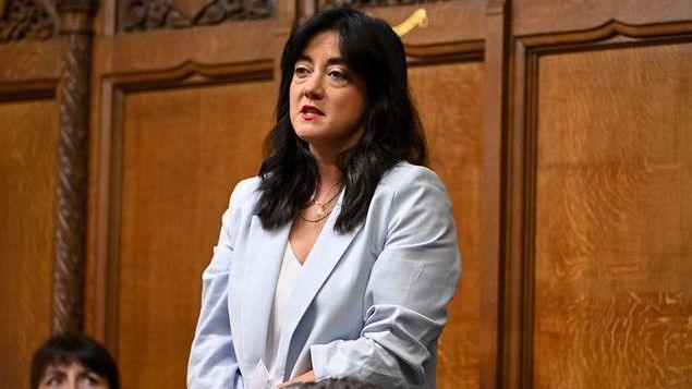 Sarah Owen wears a pale lavender jacket and stands up in the House of Commons where she is speaking.