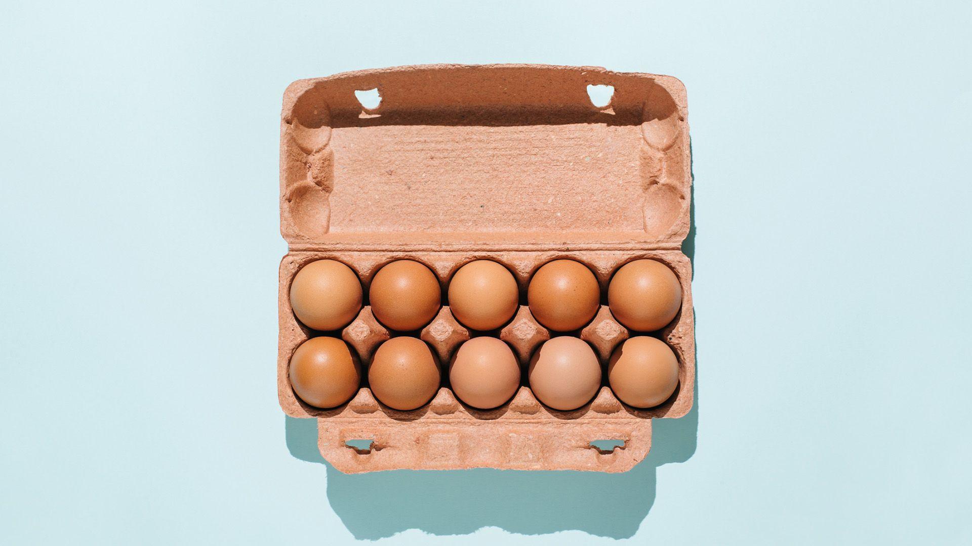 An open box of eggs on a blue surface