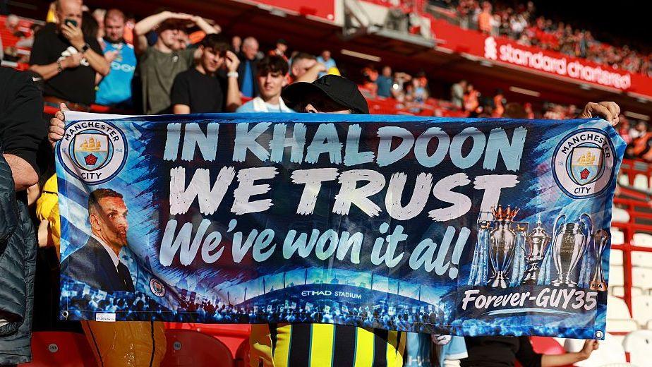 Manchester City fans hold a banner supporting chairman Khaldoon Al Mubarak at Anfield