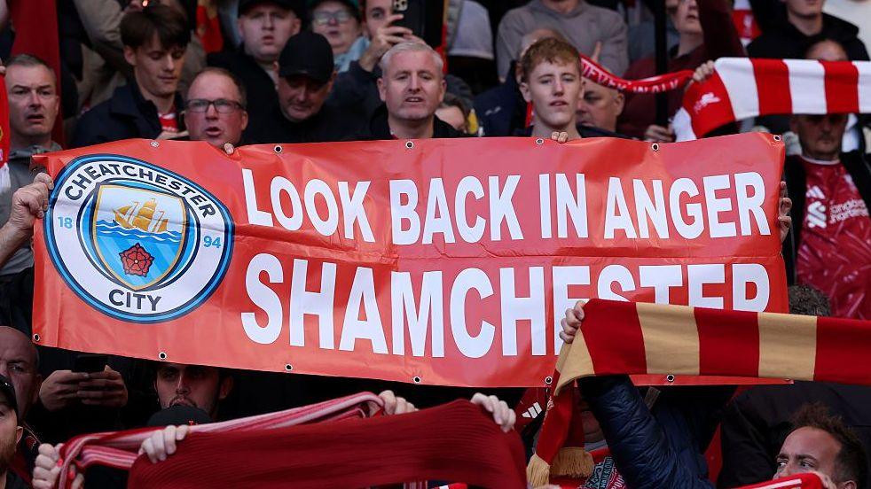 Liverpool fans holding up banners at Anfield calling Manchester City 'Cheatchester' and 'Shamchester'