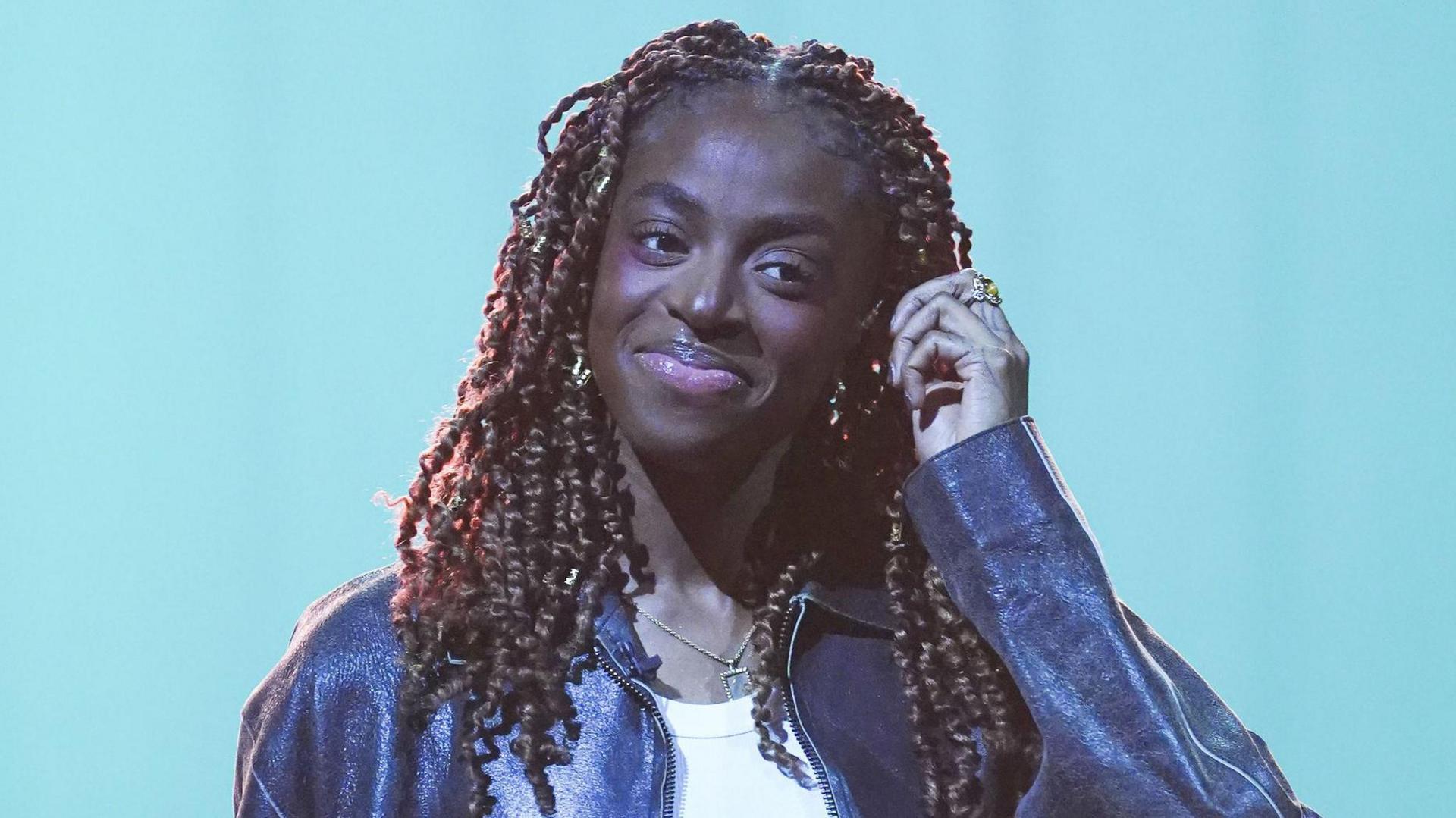 Cat Burns pictured smiling and wearing a leather jacket during filming for the Graham Norton Show in December