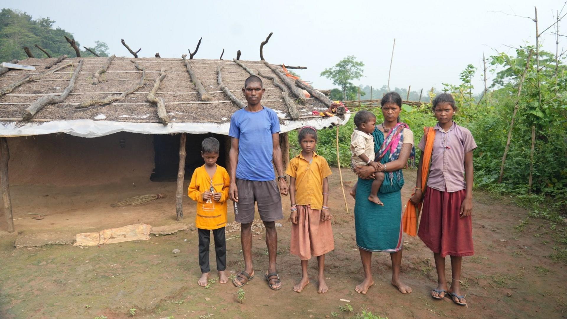 A family of six standing in front of a mud hut in a remote village in India's Madhya Pradesh state